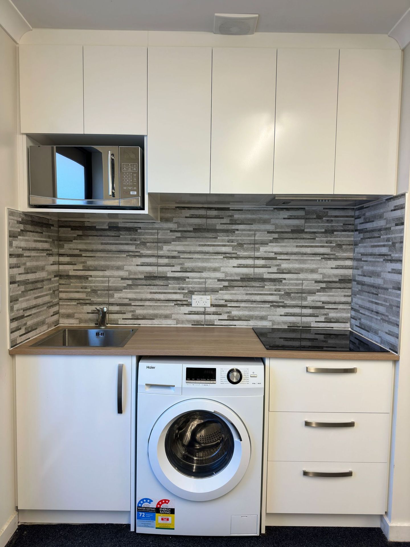 A kitchen with a washer and dryer and a microwave