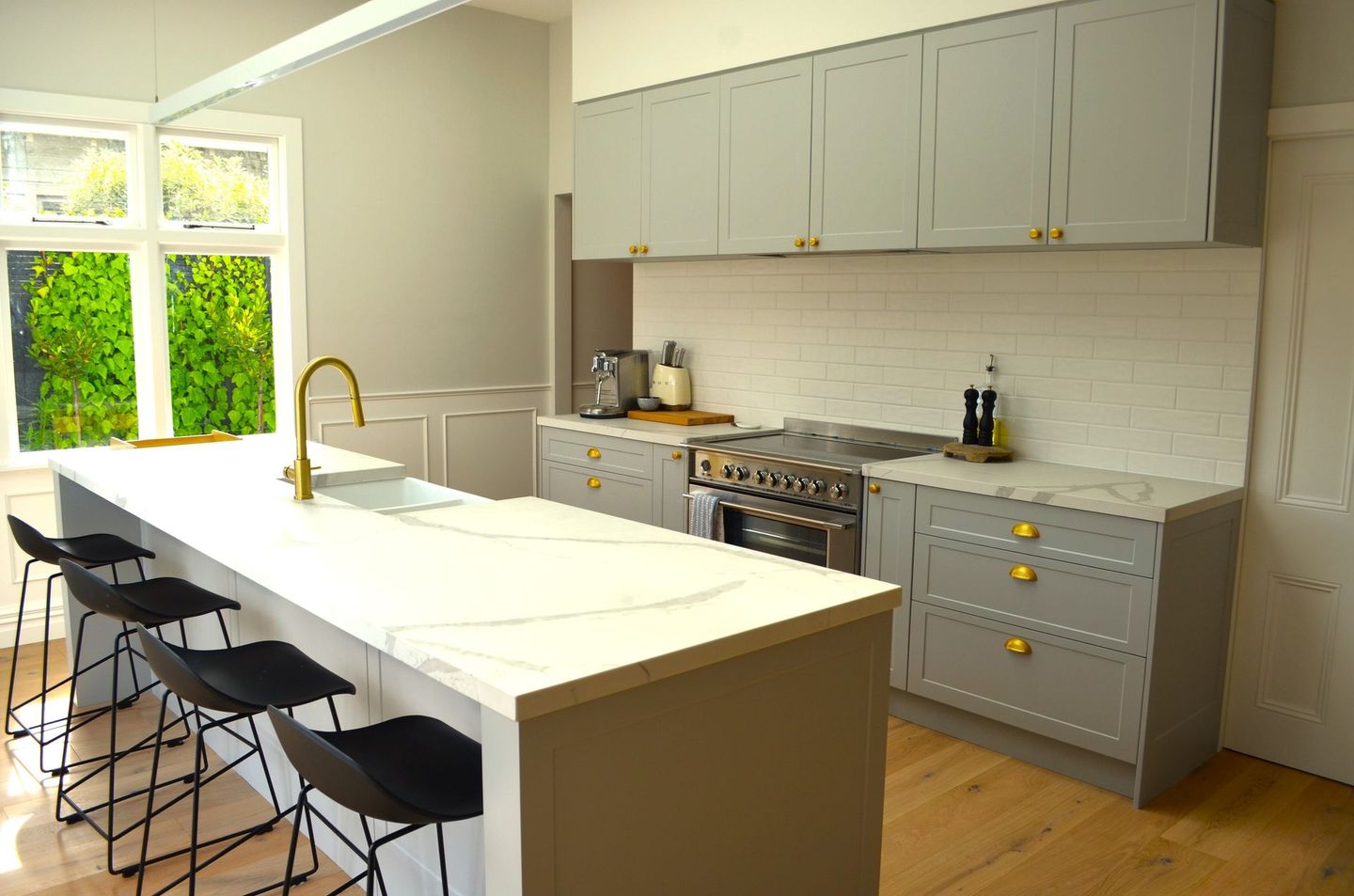 A kitchen with a large island , stove , sink , and stools.