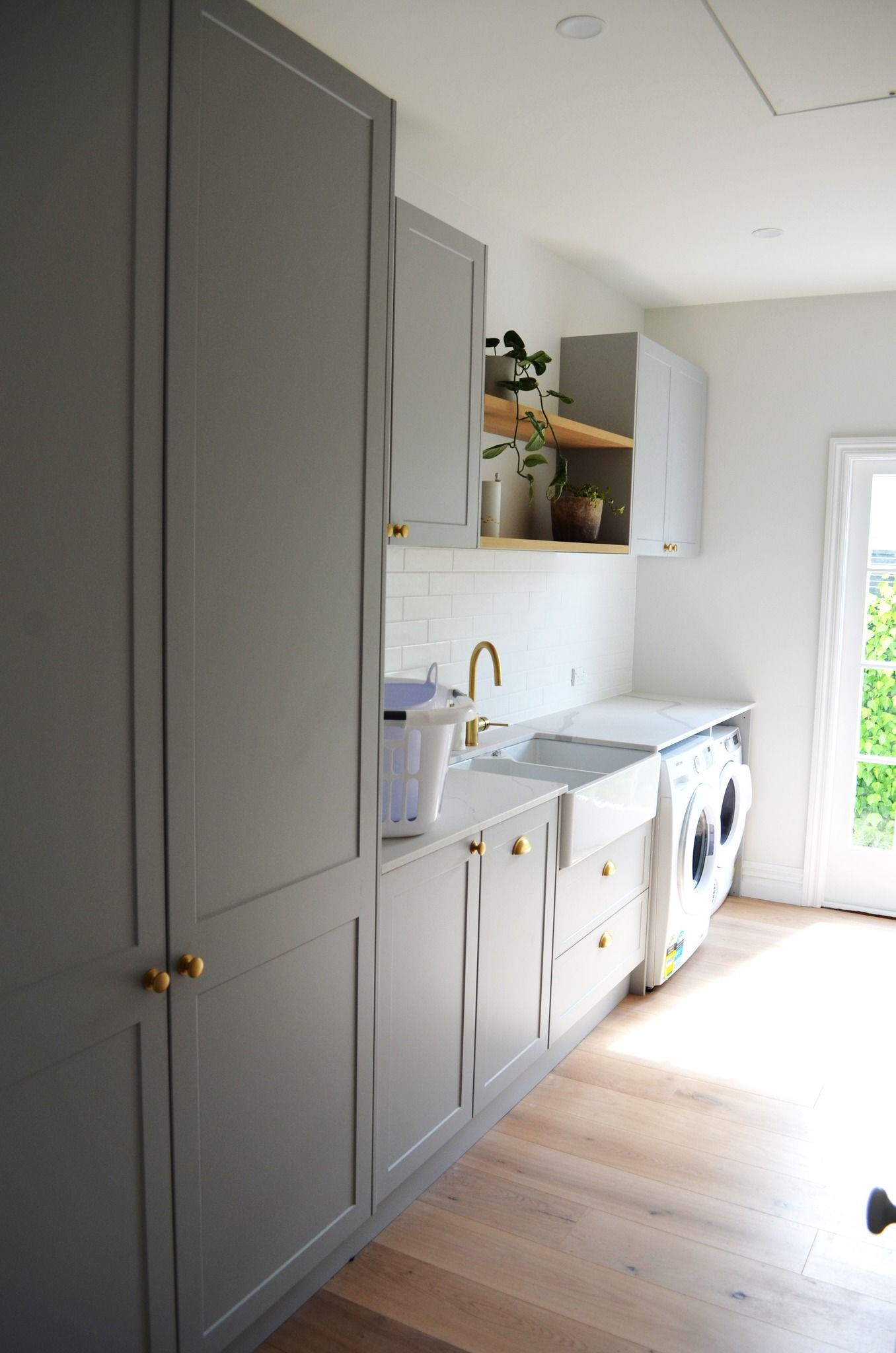 A laundry room with gray cabinets , a sink , and a washer and dryer.