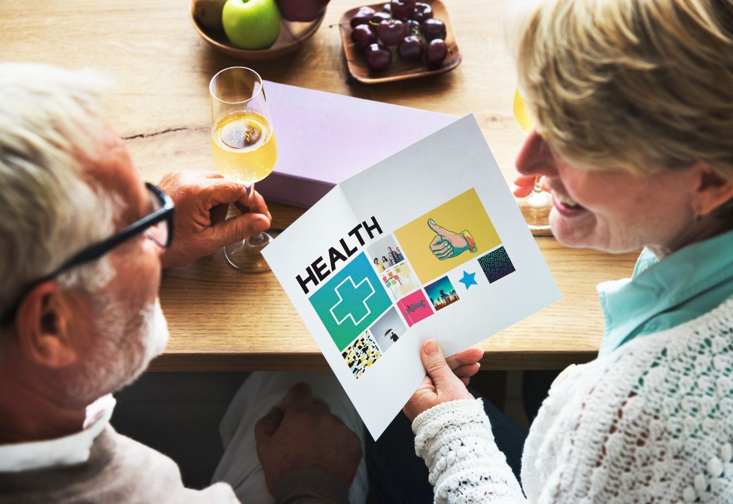 An older person and a younger person looking at a laptop, smiling. The younger person holds a credit card.