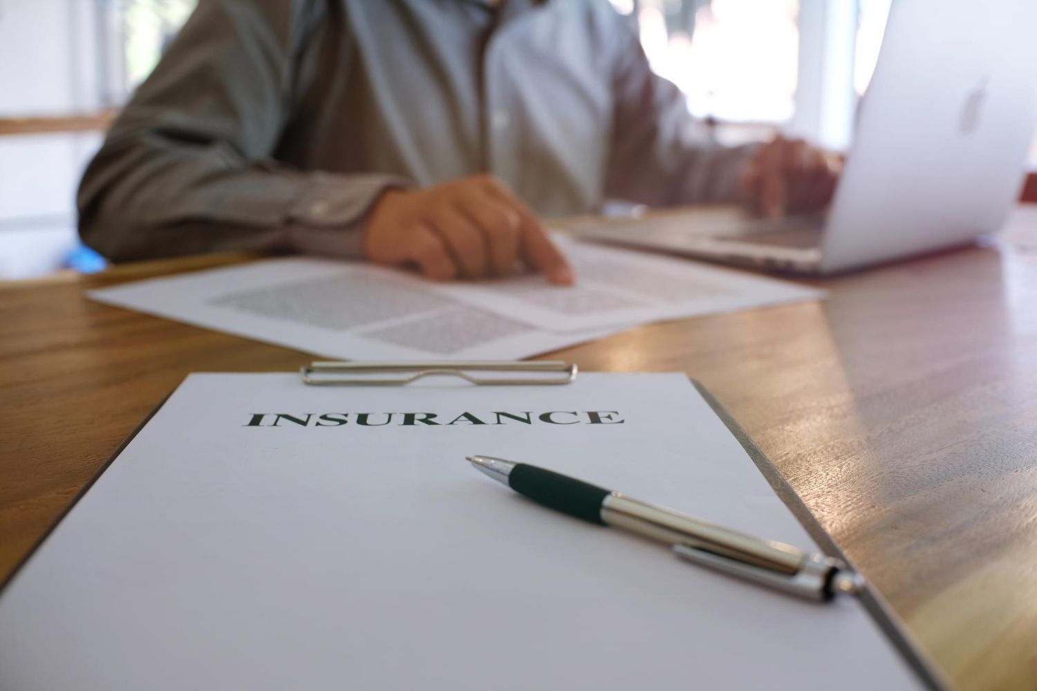 Hands stacked together with a healthcare provider in the background.