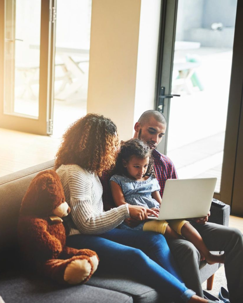 Grandparents and child walking hand-in-hand on a forest trail with wooden railing.