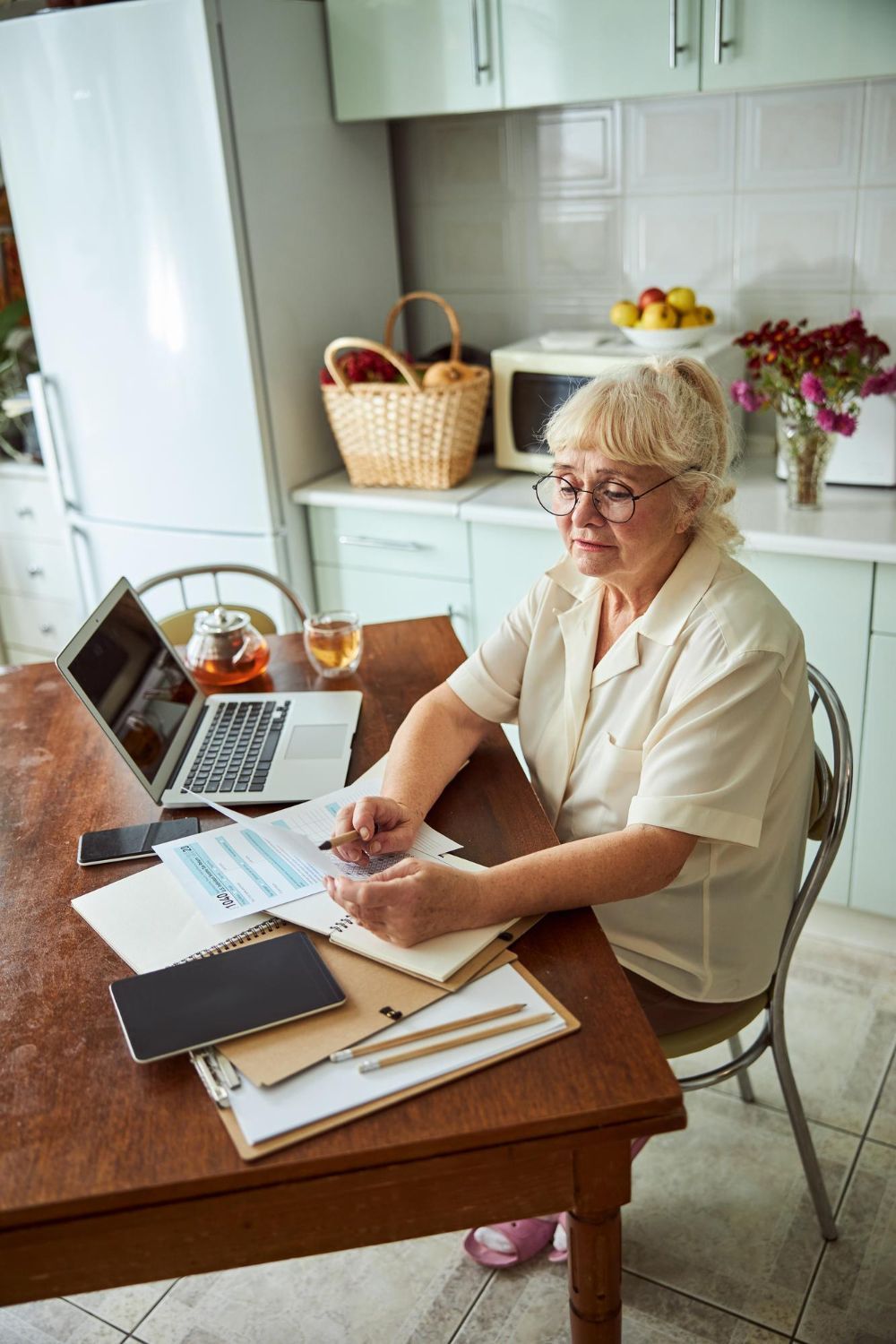 An older person and a younger person looking at a laptop, smiling. The younger person holds a credit card.