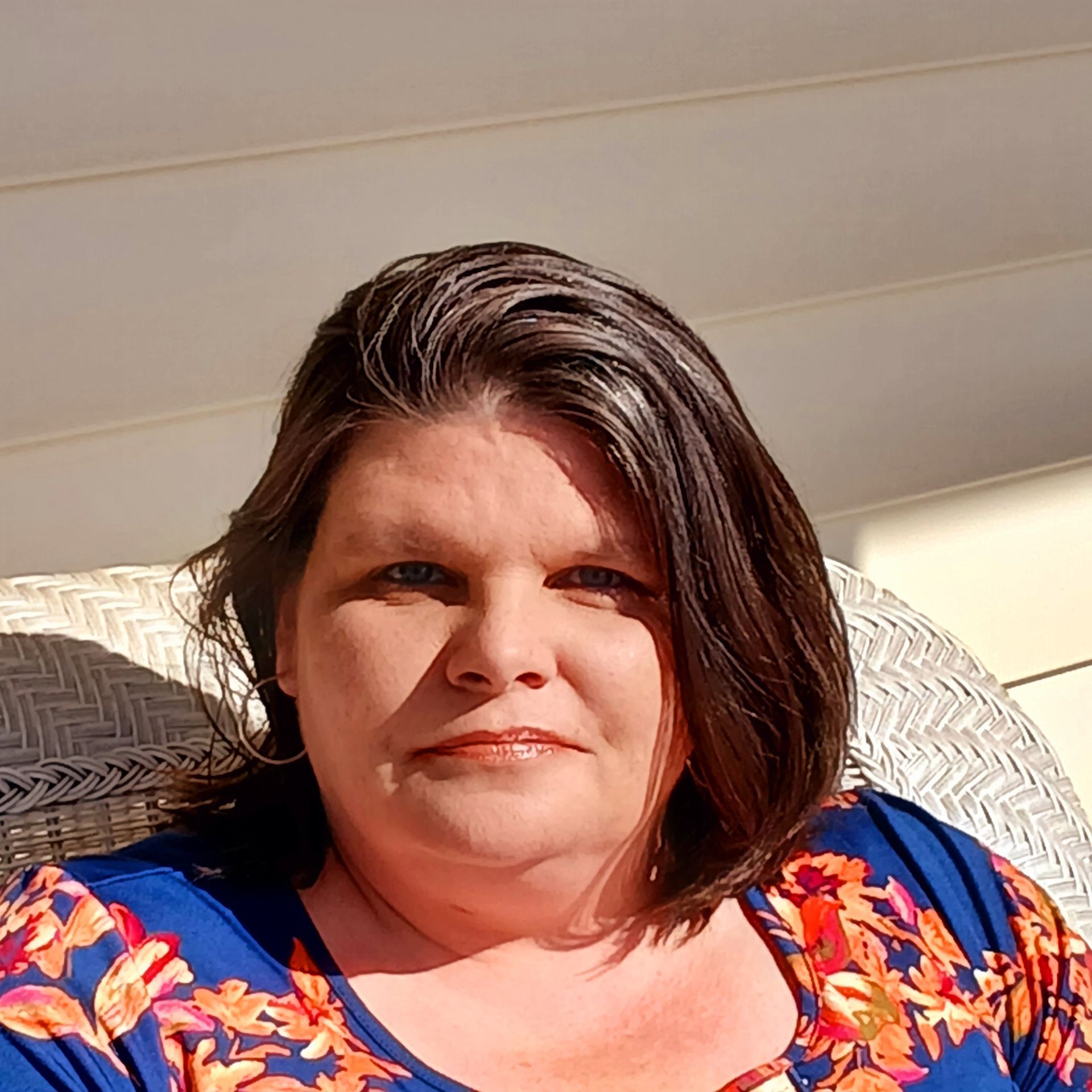 Woman wearing glasses and blazer, smiling. Against a blue background.