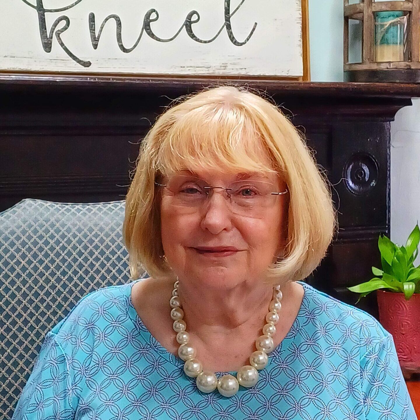 Man in a black suit with a red tie and pocket square, smiling against a dark background.