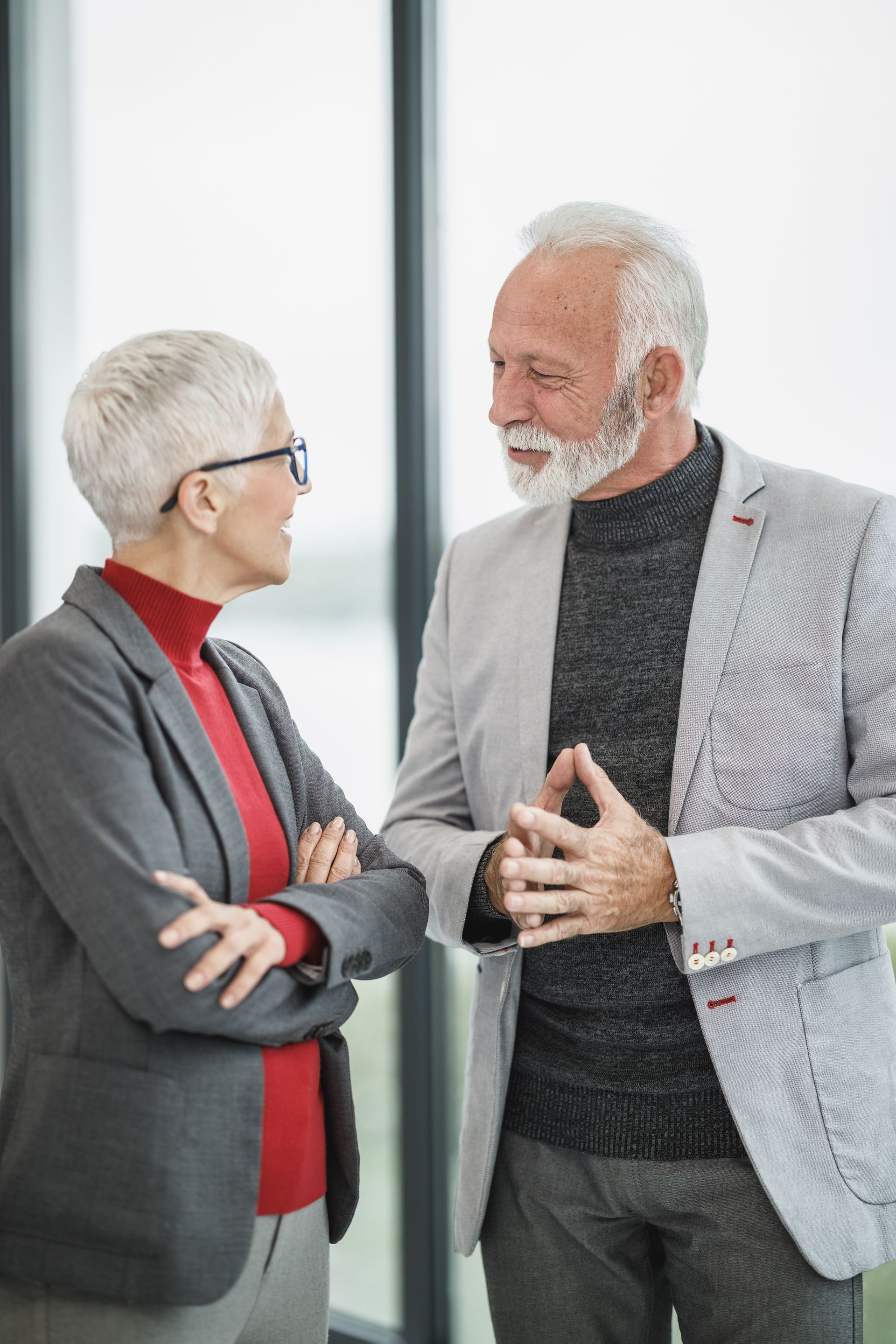 People enjoying a meal outdoors. Man grilling food, woman holding a glass. Sunlight illuminates the scene.