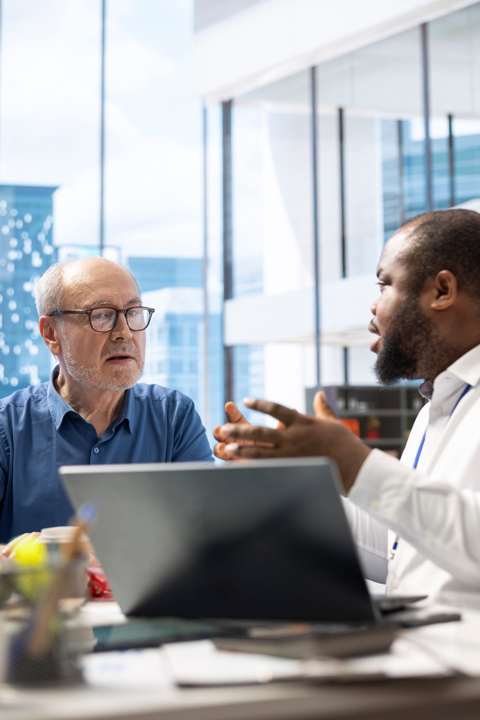 People enjoying a meal outdoors. Man grilling food, woman holding a glass. Sunlight illuminates the scene.