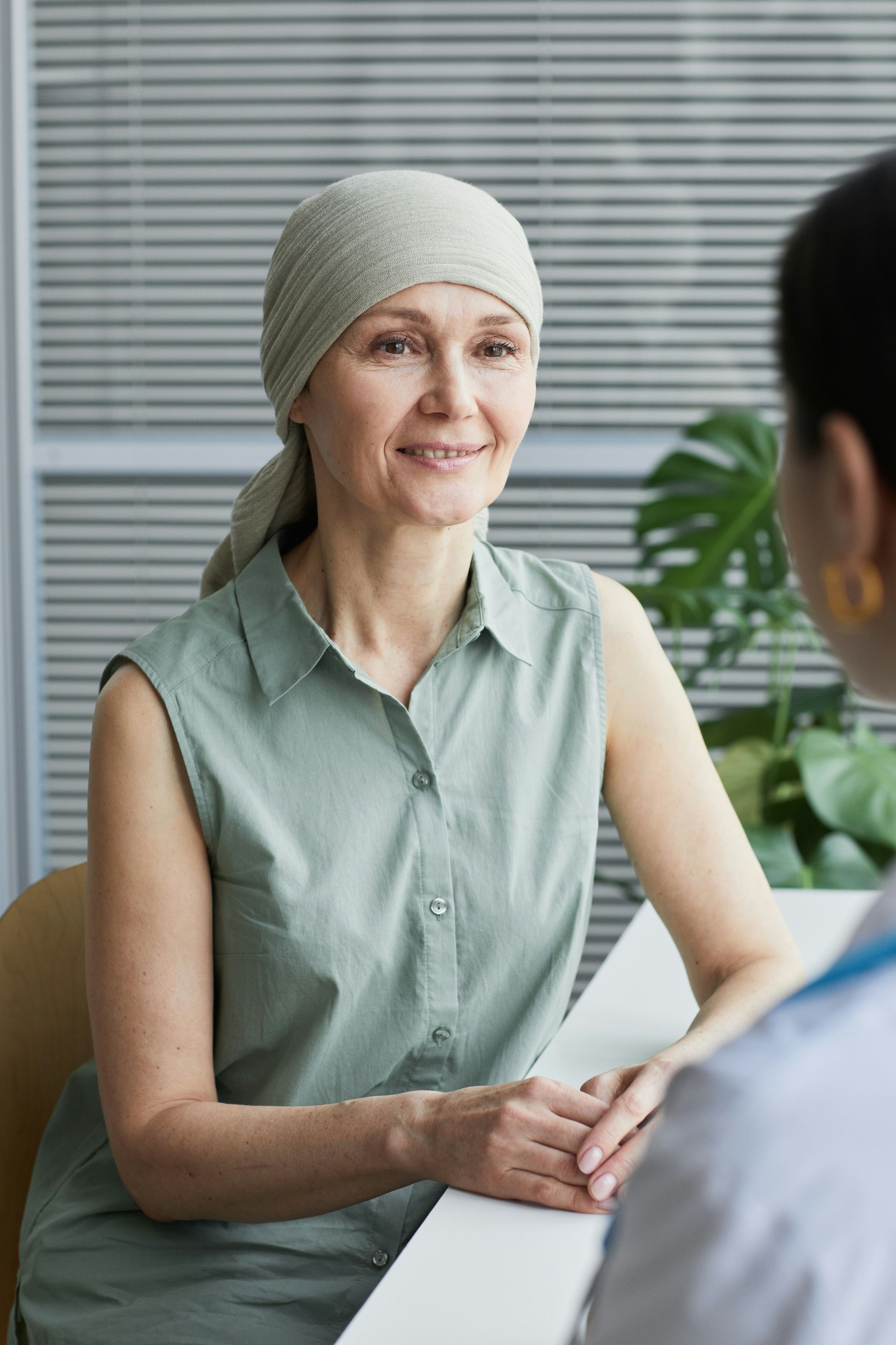 People enjoying a meal outdoors. Man grilling food, woman holding a glass. Sunlight illuminates the scene.