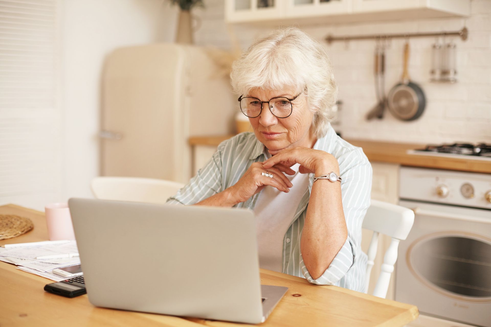 An older person and a younger person looking at a laptop, smiling. The younger person holds a credit card.