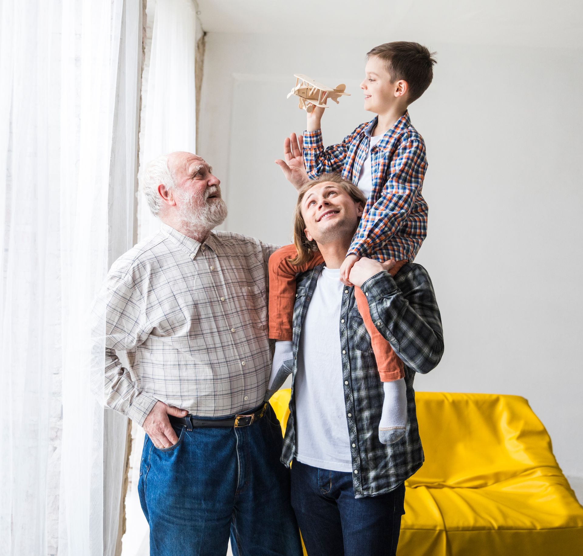 Grandparents and child walking hand-in-hand on a forest trail with wooden railing.