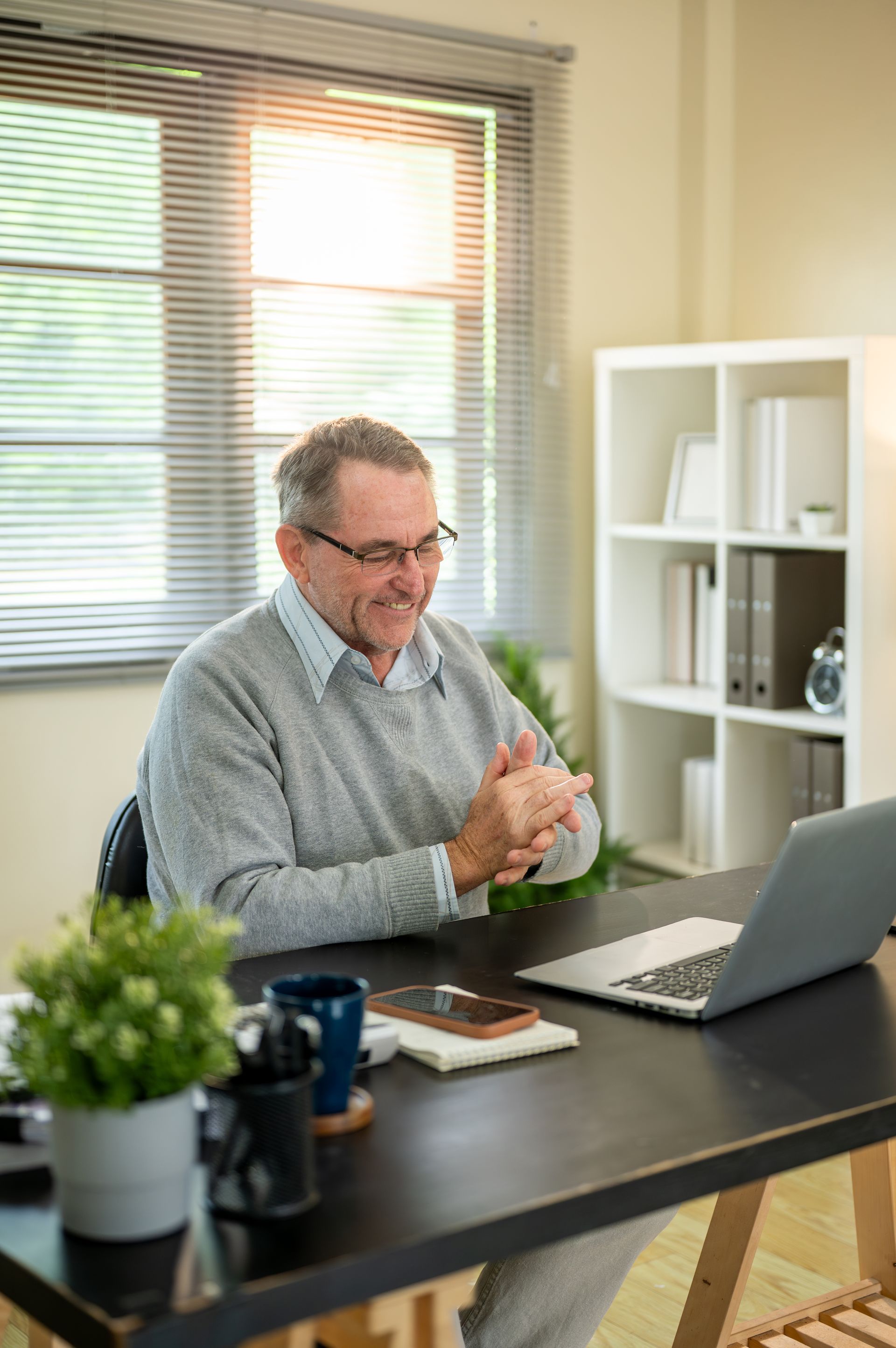 Hands stacked together with a healthcare provider in the background.