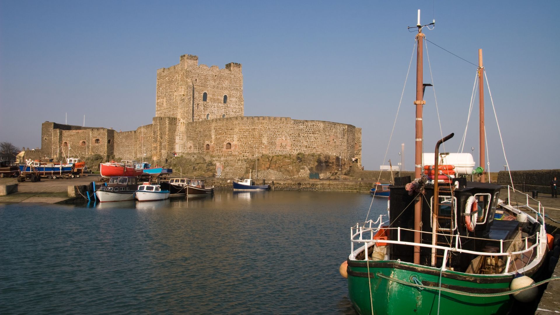 Castle with harbor and docked fishing boats on a sunny day.