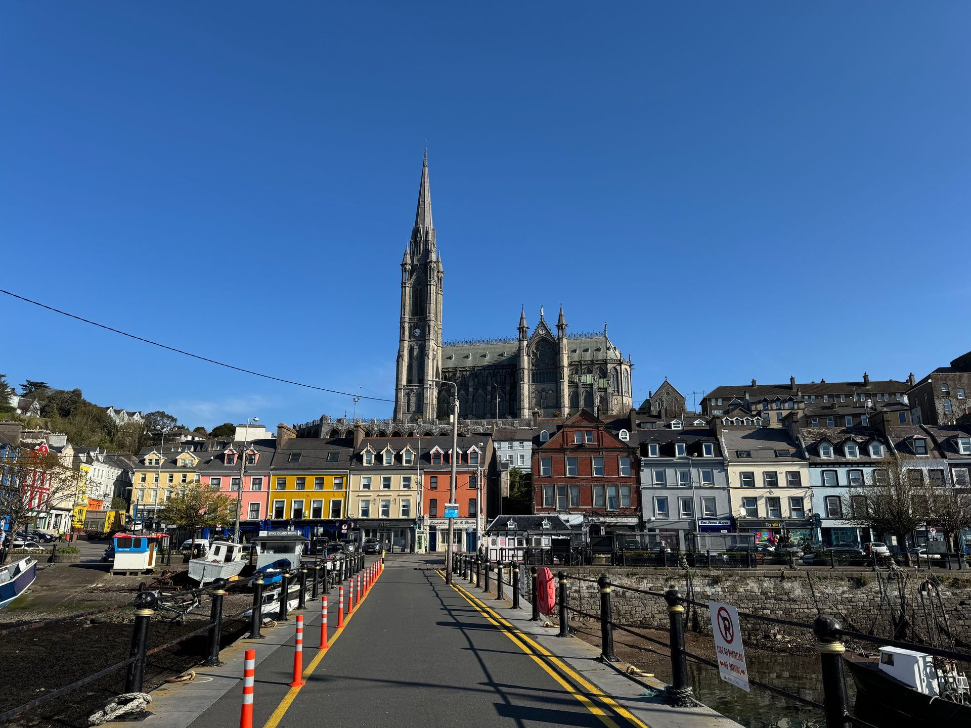 Cobh, Ireland, waterfront with colorful buildings, a cathedral, and blue sky.