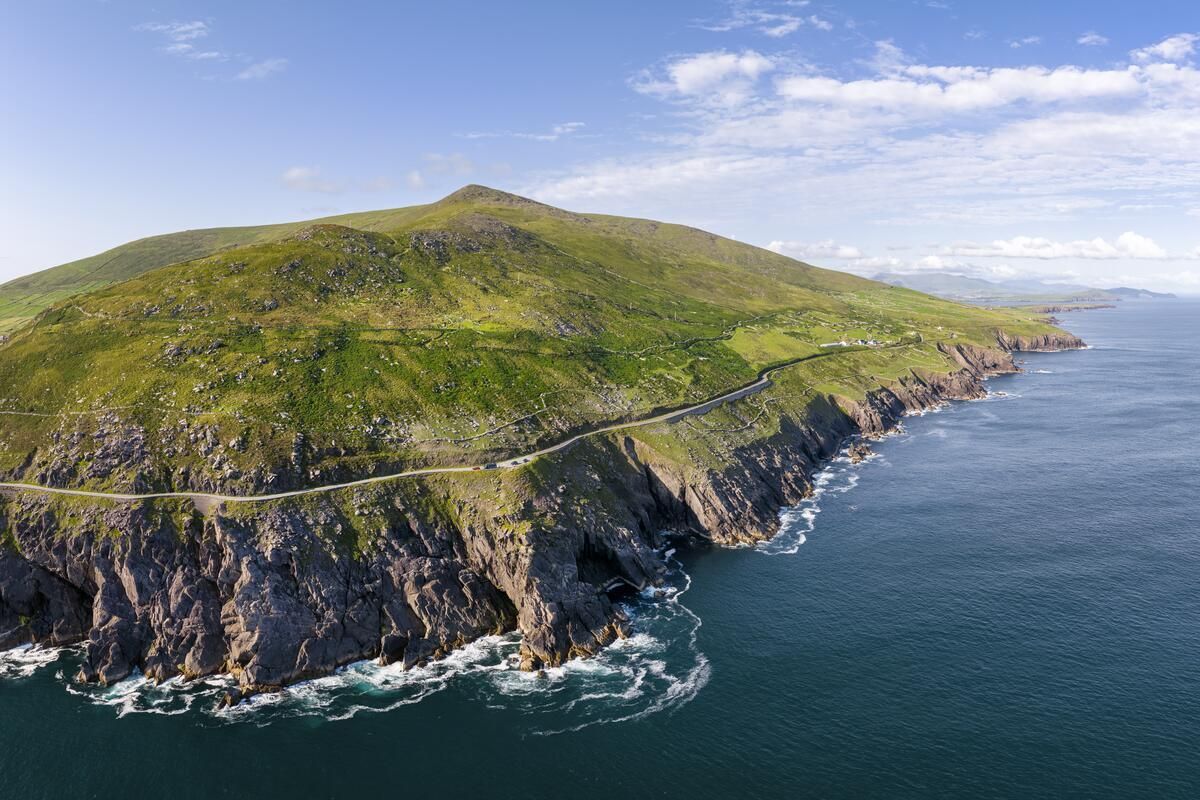 Rocky green coastline with cliffs and ocean under a partly cloudy sky