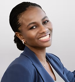 Smiling Black woman in a blue blazer, looking towards the camera. Her hair is styled back.