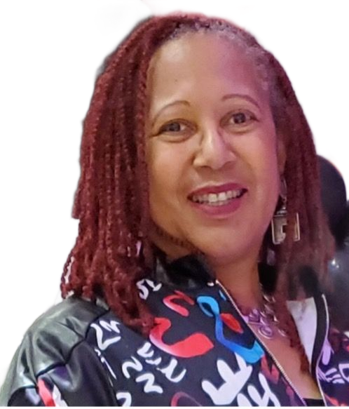 Woman with dreadlocks wearing glasses, a black top, a black and white blazer, and large earrings smiles at the camera.