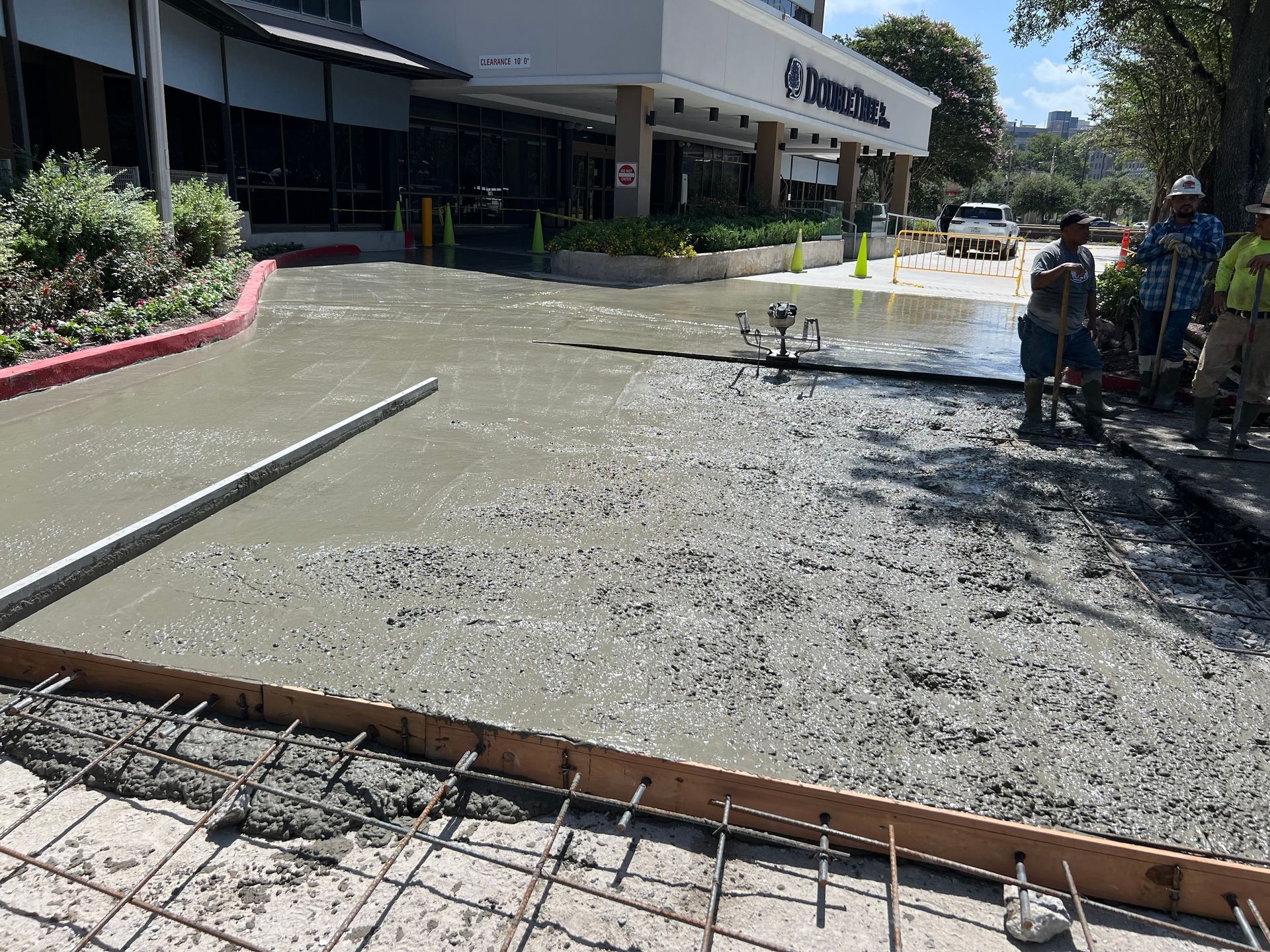 Workers pouring concrete for a driveway. Building in the background.
