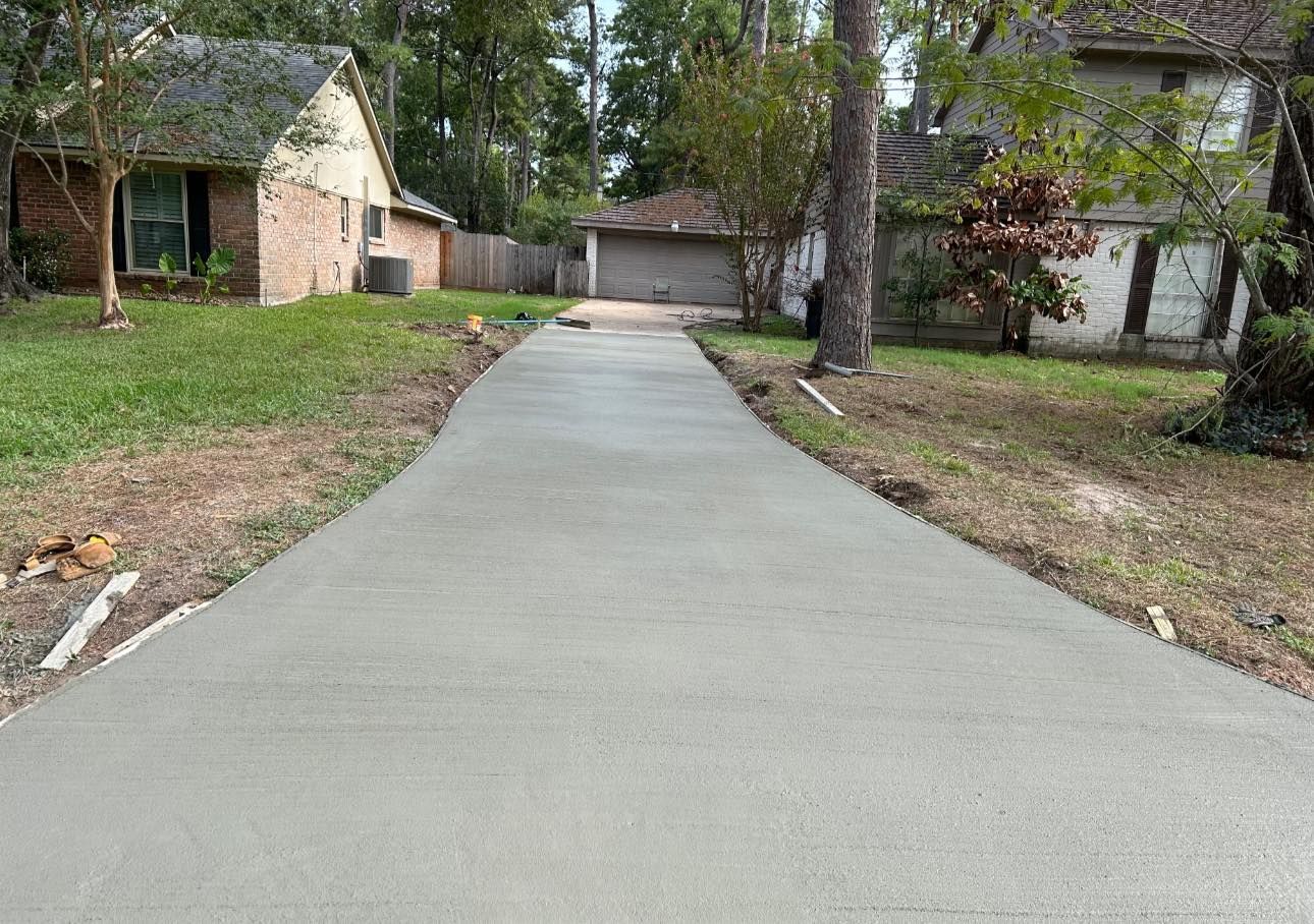 Newly poured concrete driveway leading to a garage, with a house on the left.