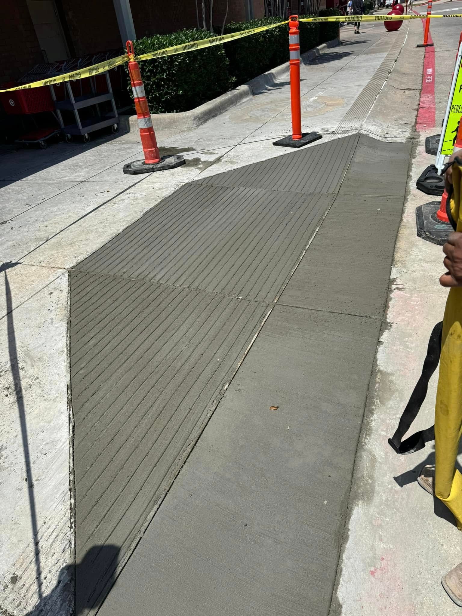 Concrete sidewalk construction with orange cones and caution tape.