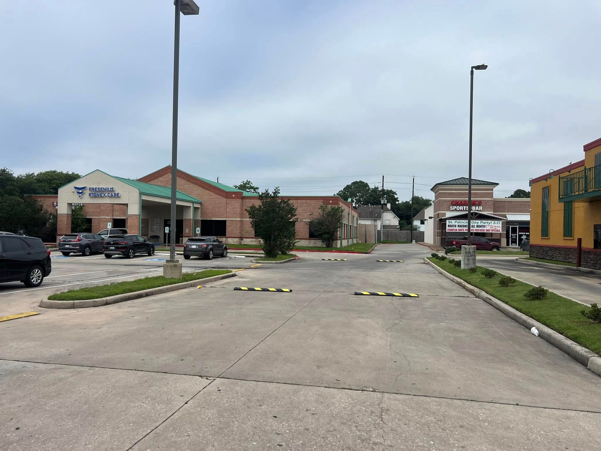 A building with parking lot and cars under a cloudy sky.