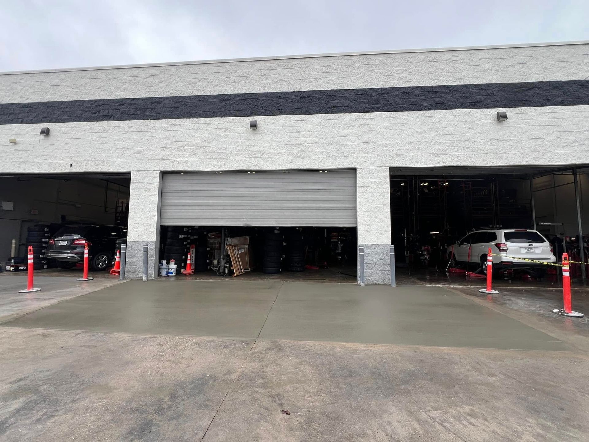 Car wash exterior with three bays. Two cars inside, one in each end bay, and the center bay is open.