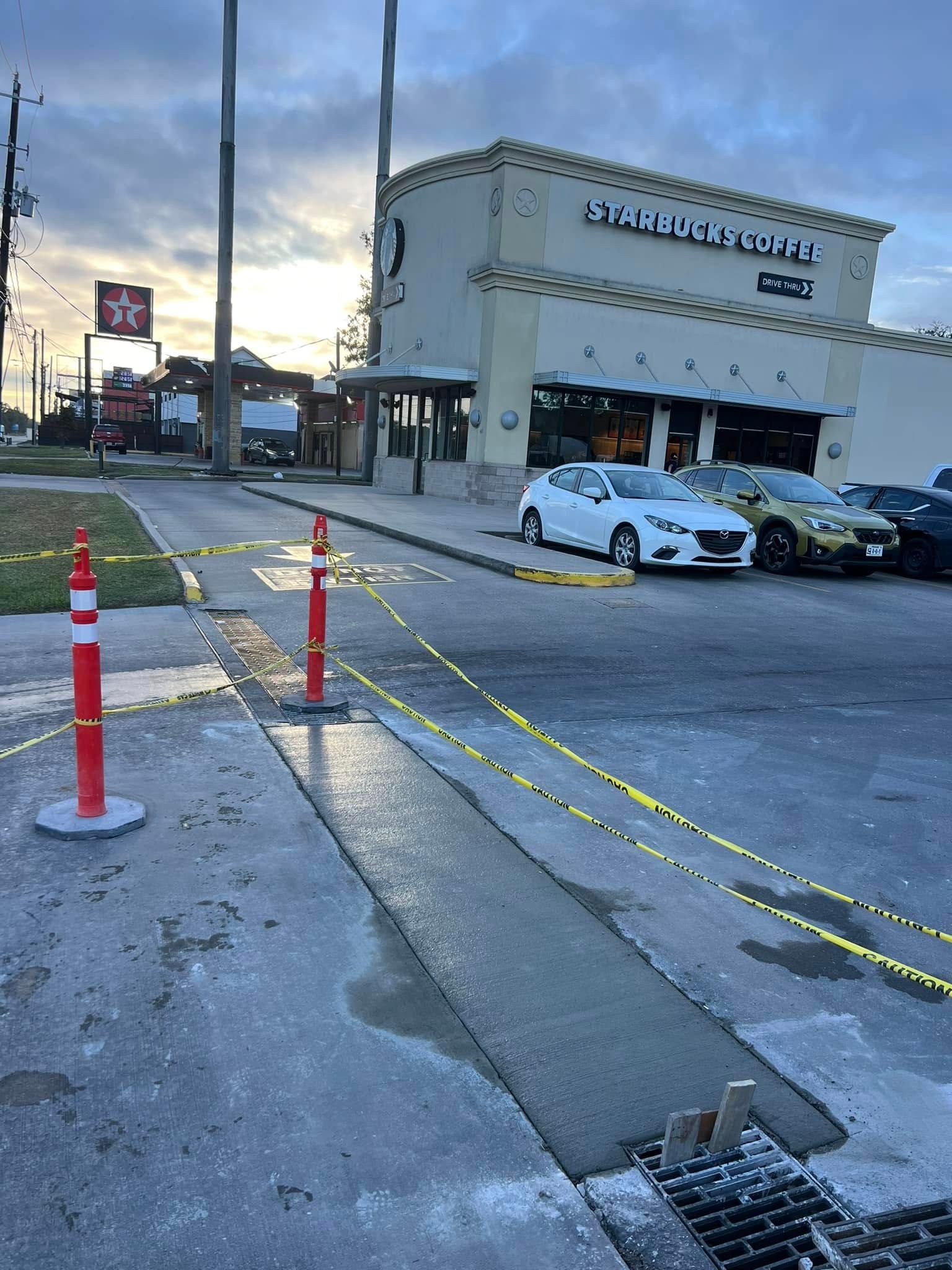 Driveway concrete repair in front of a Starbucks with caution tape and pylons.