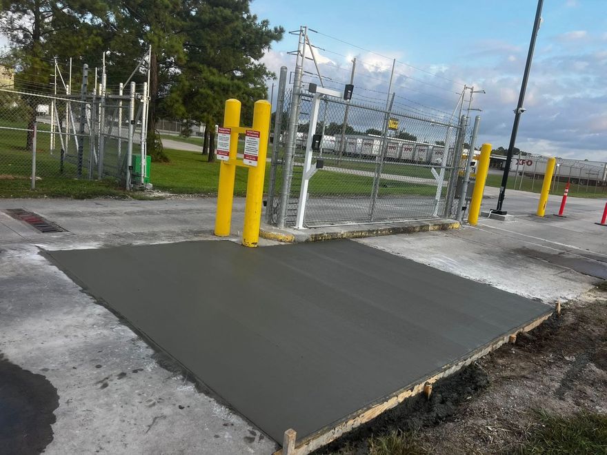 Freshly poured concrete driveway with an orange traffic cone, in front of a house.