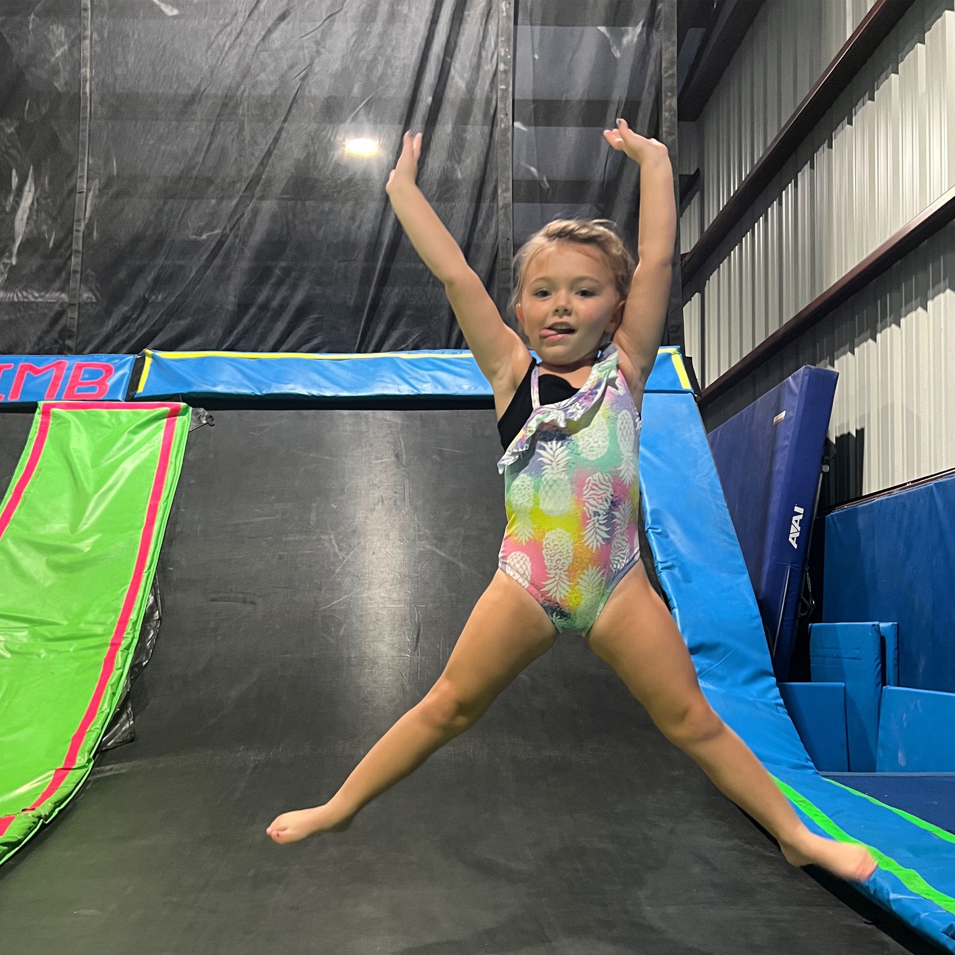 A little girl is jumping on a trampoline with her arms in the air