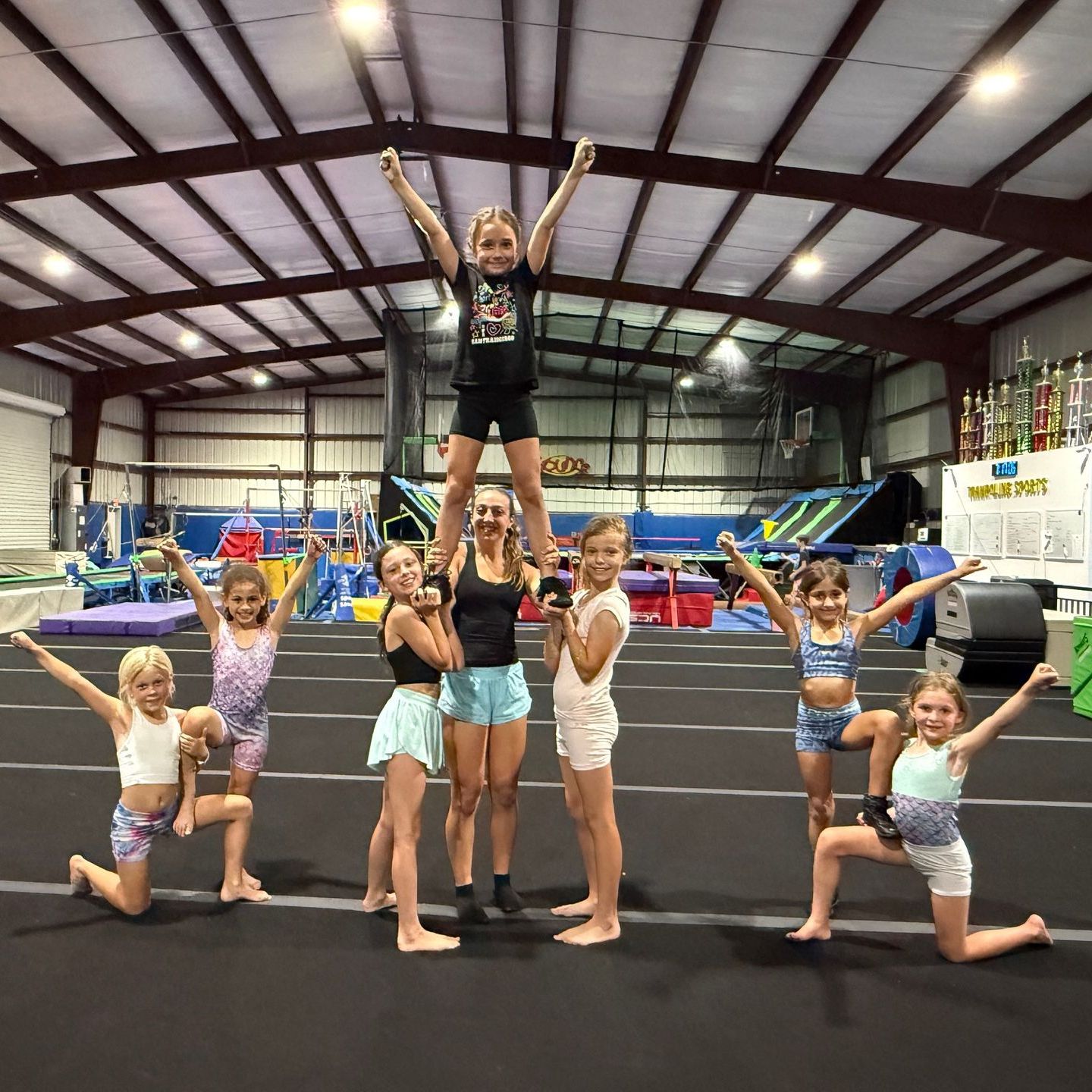 A group of young girls are posing for a picture in a gym.