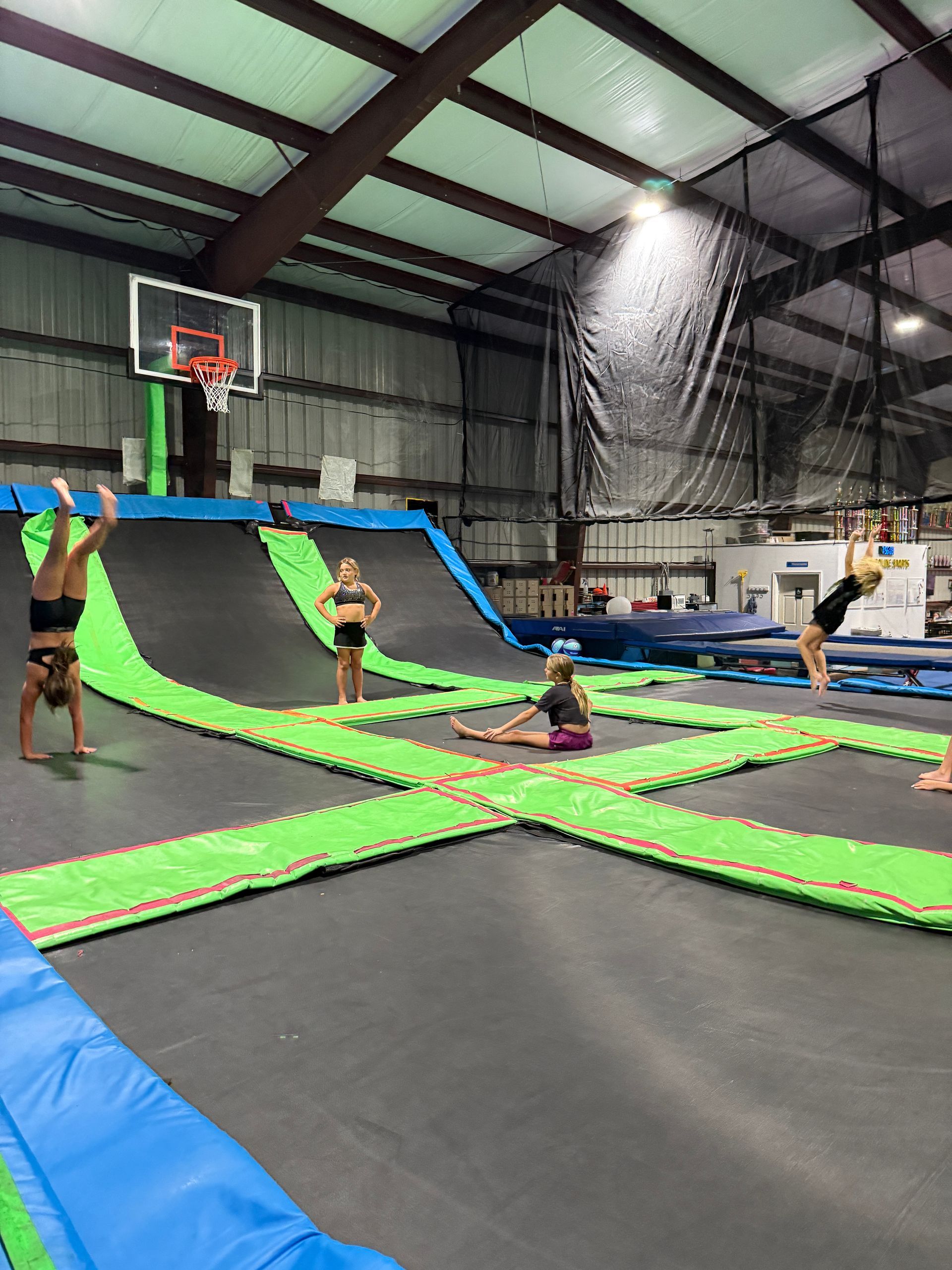 A group of children are doing handstands on a trampoline in a gym.