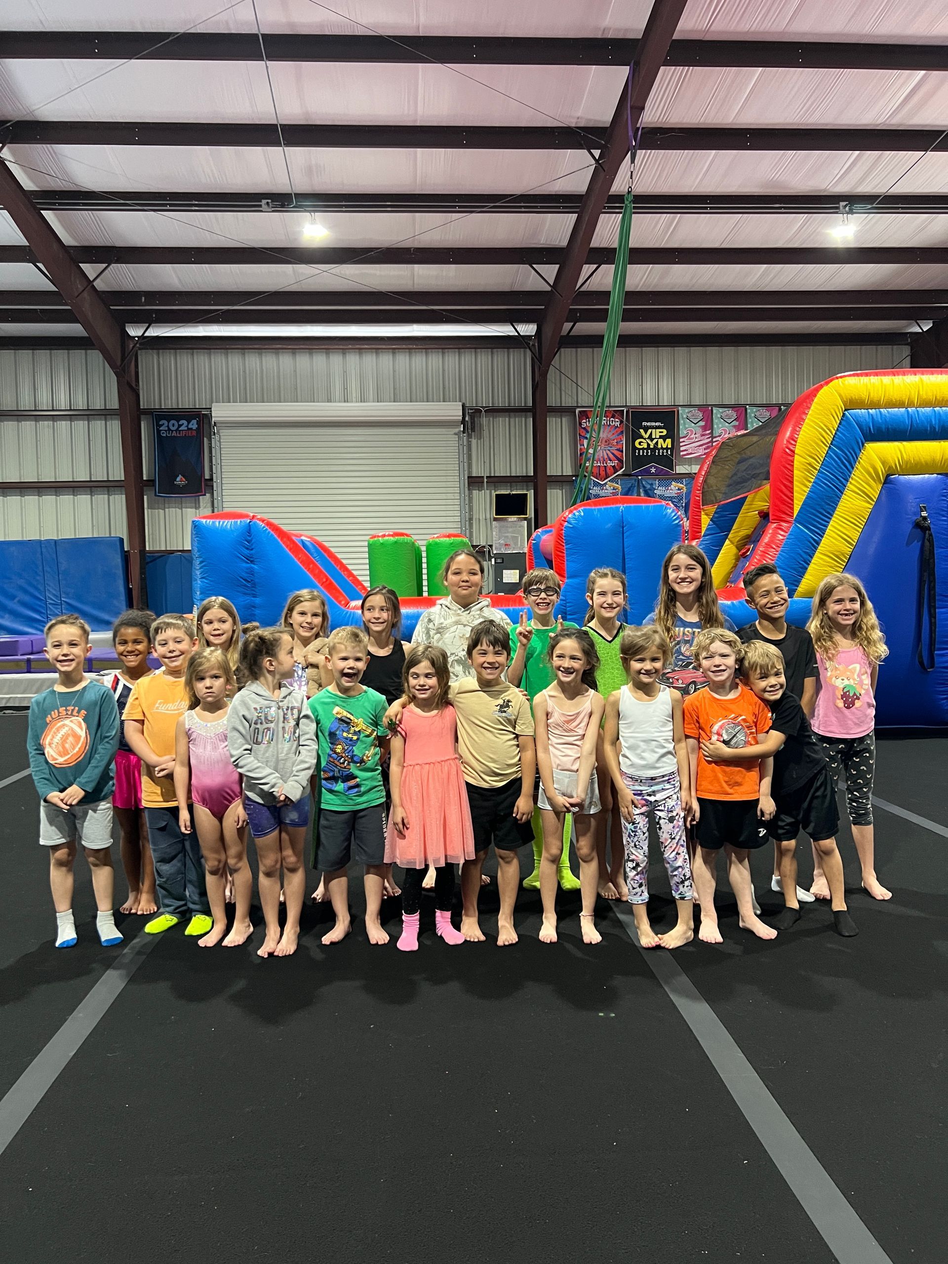 A group of children are posing for a picture in front of a bouncy house.