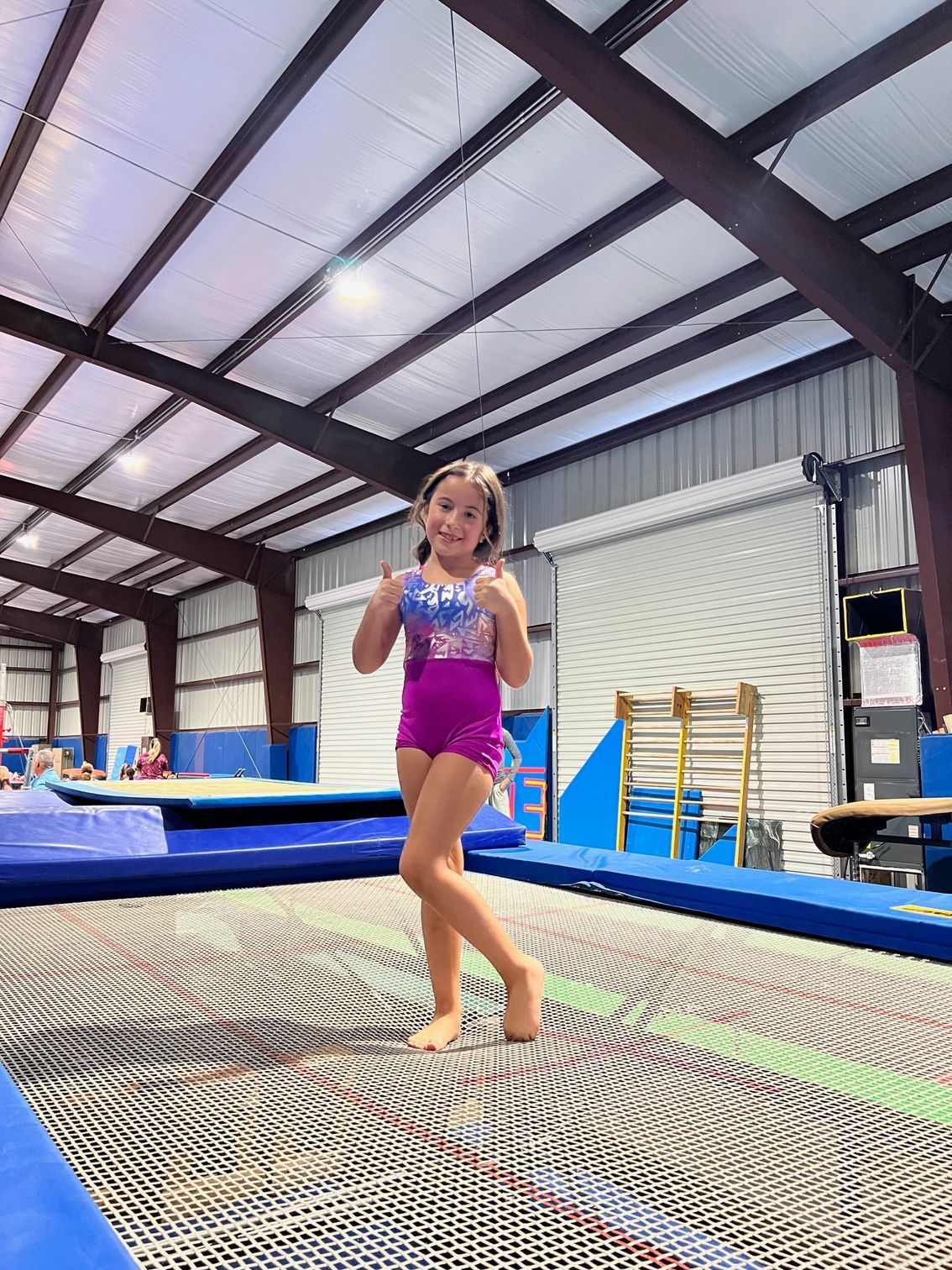 A group of children are doing handstands on a trampoline in a gym.
