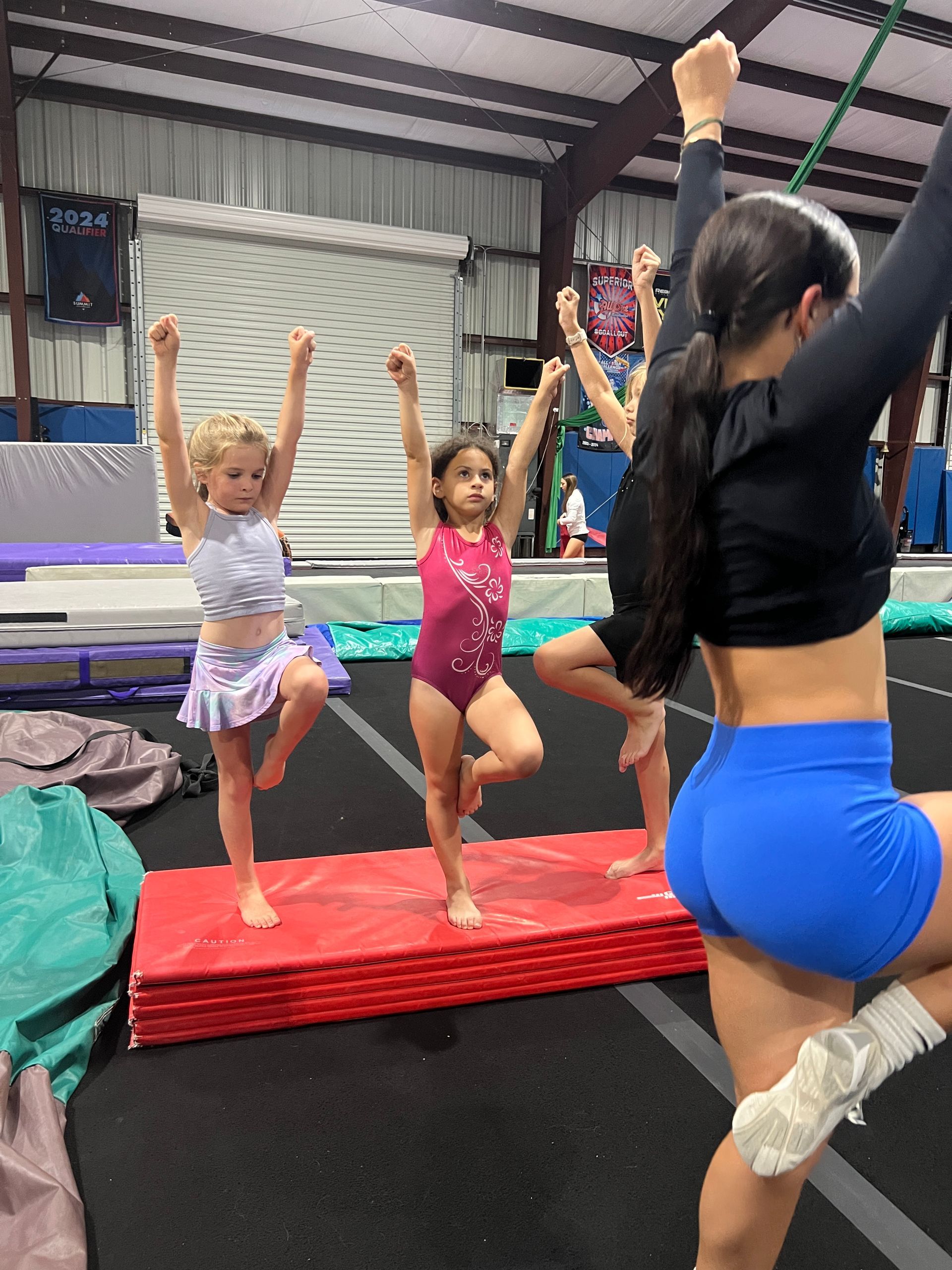 A group of young girls are practicing gymnastics in a gym.