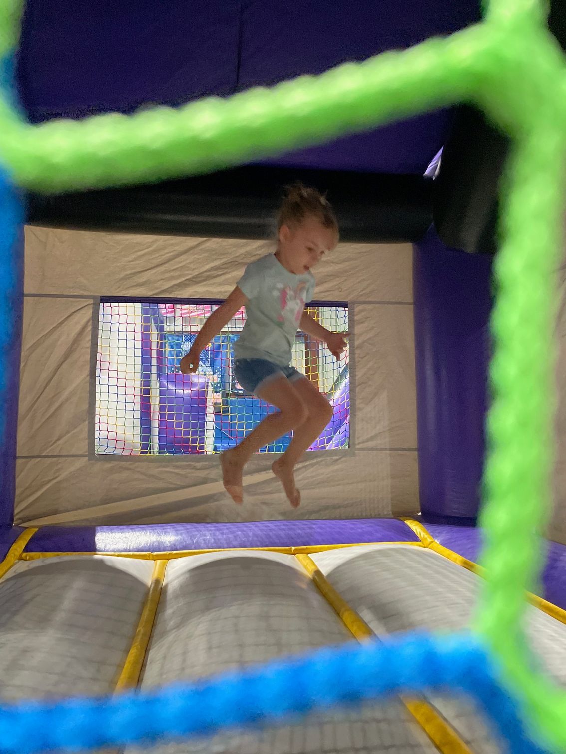 A little girl is jumping in a bouncy house.