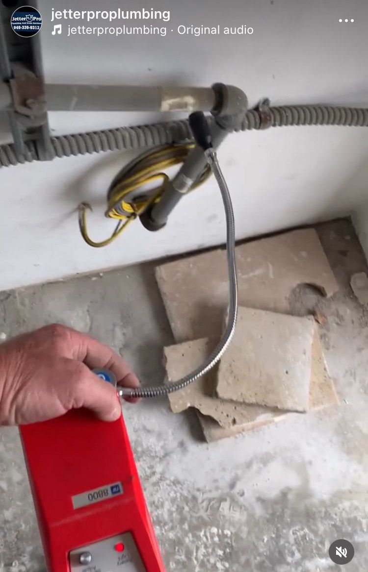 A person is using a red device to test a pipe.