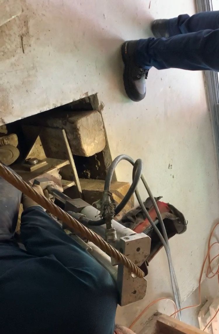 A man is using a machine to cut a hole in a wall.