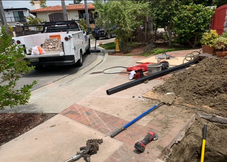 A white truck is parked on the side of the road next to a pile of dirt.