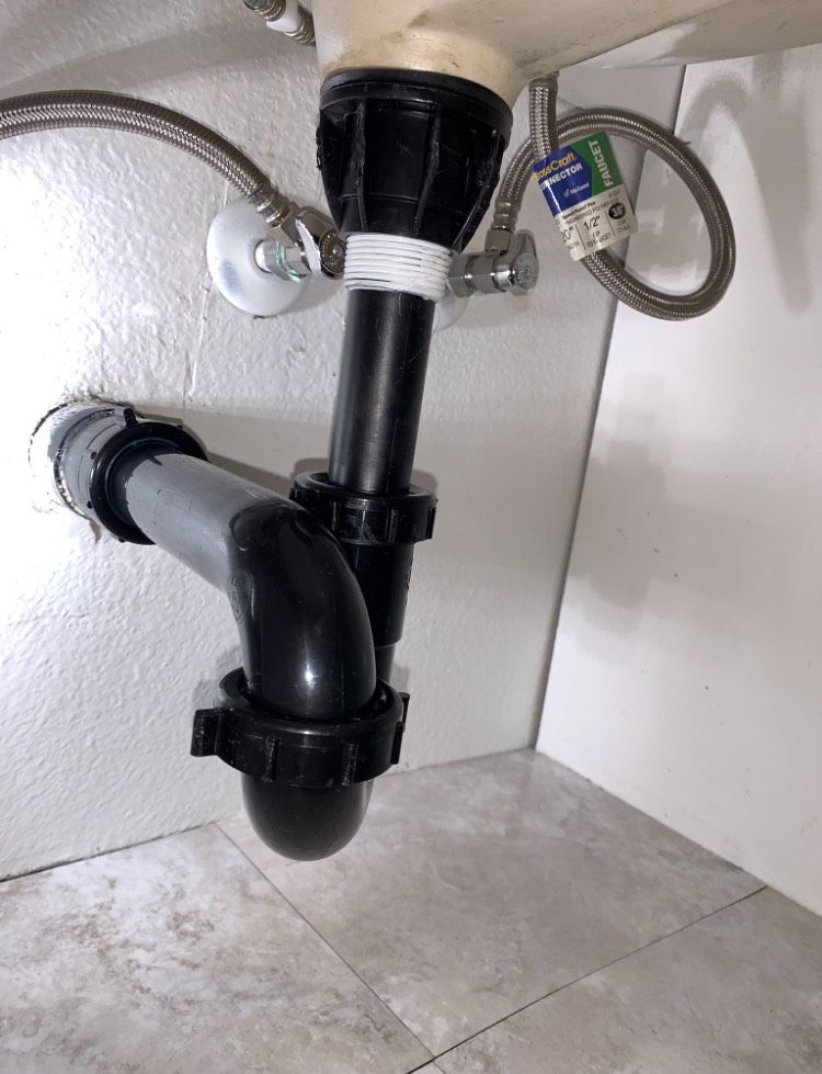 A bathroom sink with a black pipe underneath it.