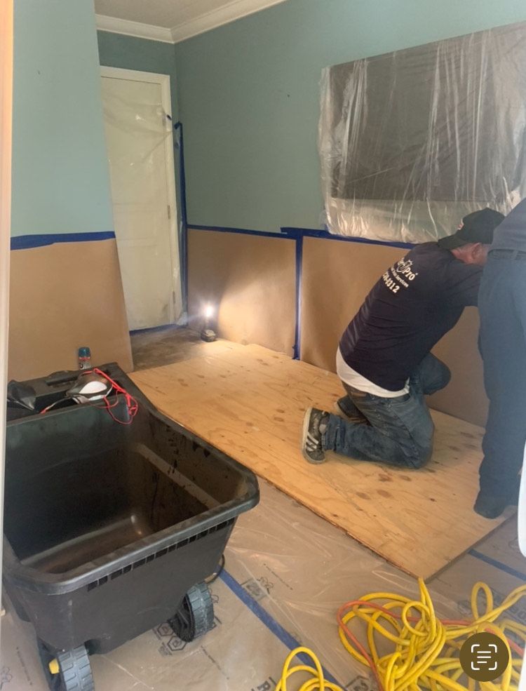 A man is kneeling on a wooden floor in a room.