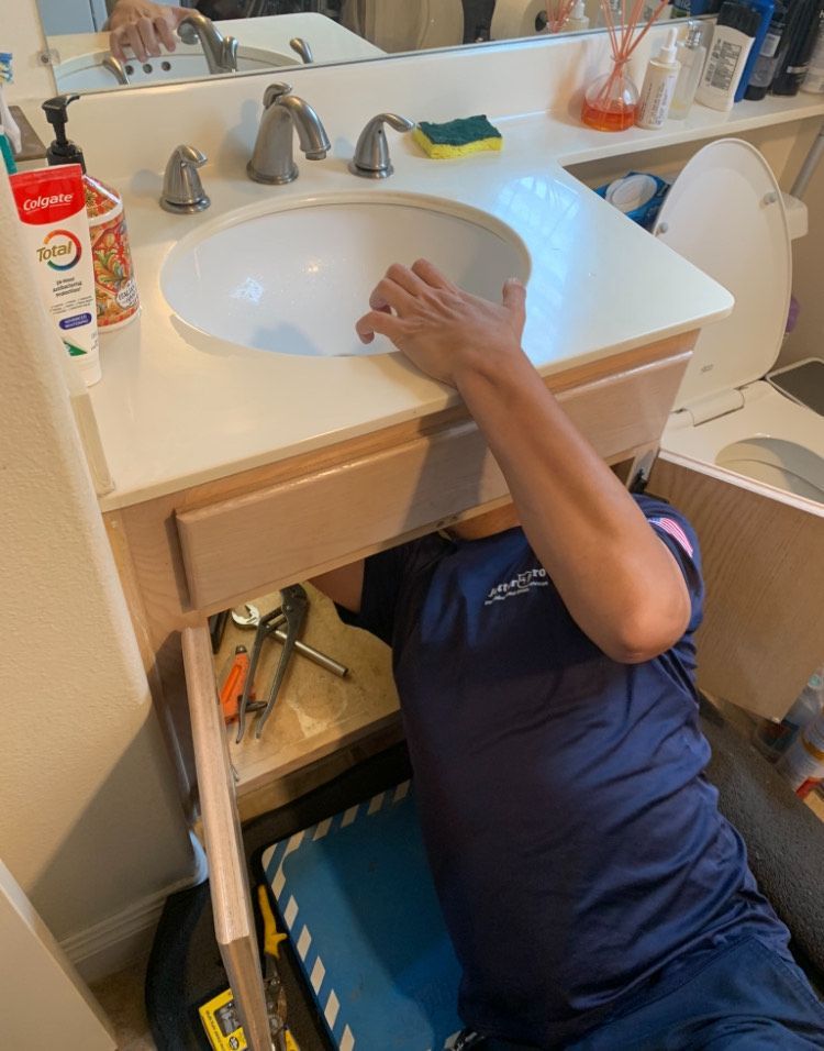 A man is fixing a sink in a bathroom.