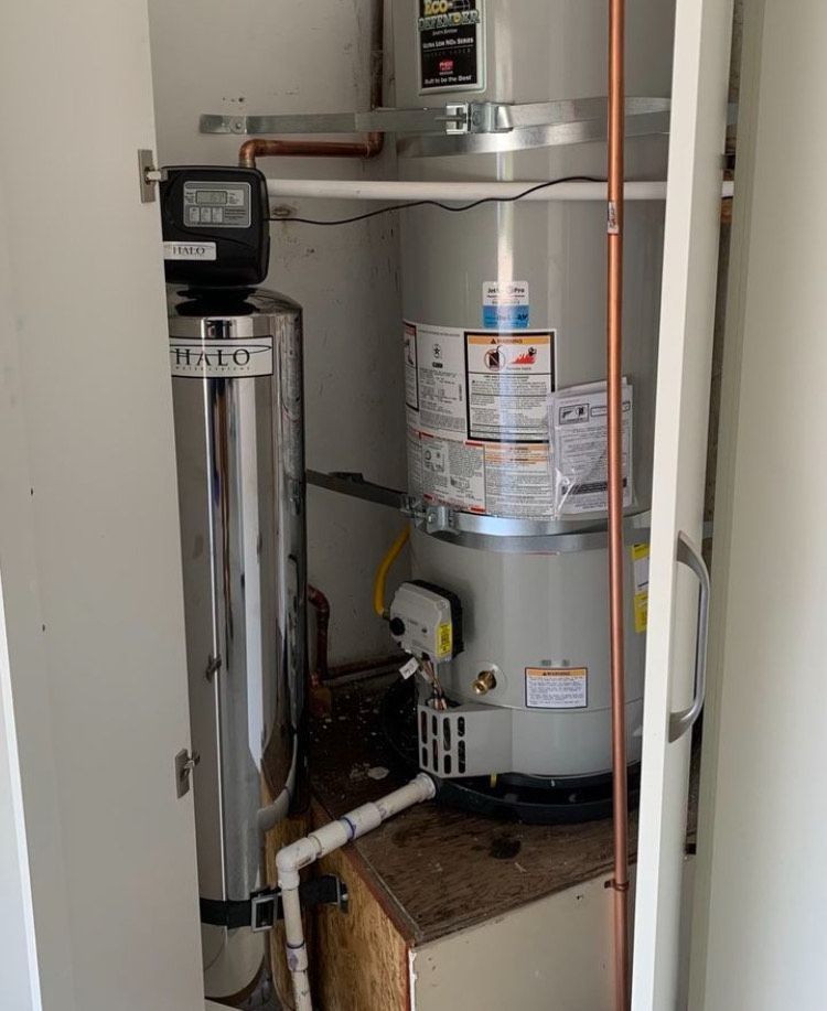 A water heater is sitting in a closet next to a water filter.