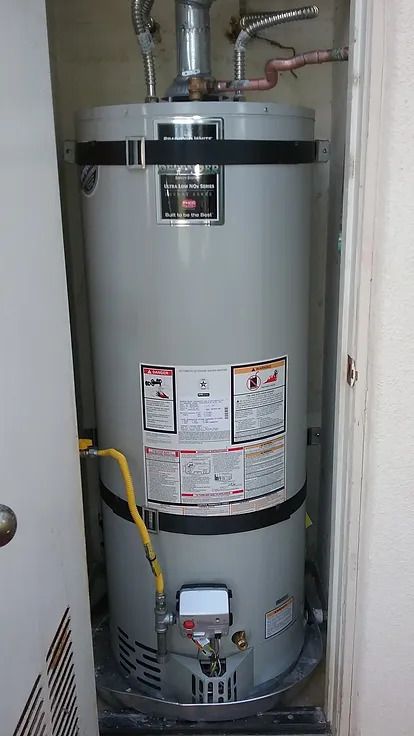 A water heater is sitting in a closet next to a door.