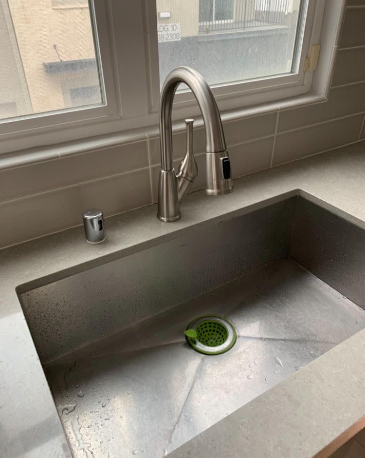 A kitchen sink with a faucet and a window in the background.