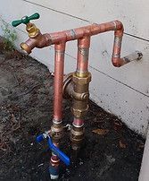 A copper pipe with a green handle and a blue ball valve.
