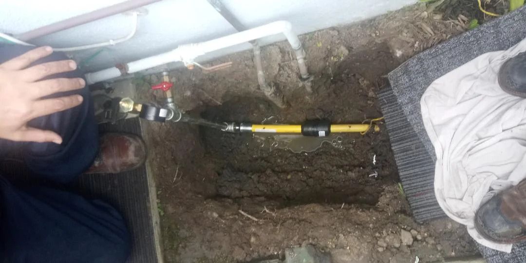 A person is fixing a gas pipe in the ground.