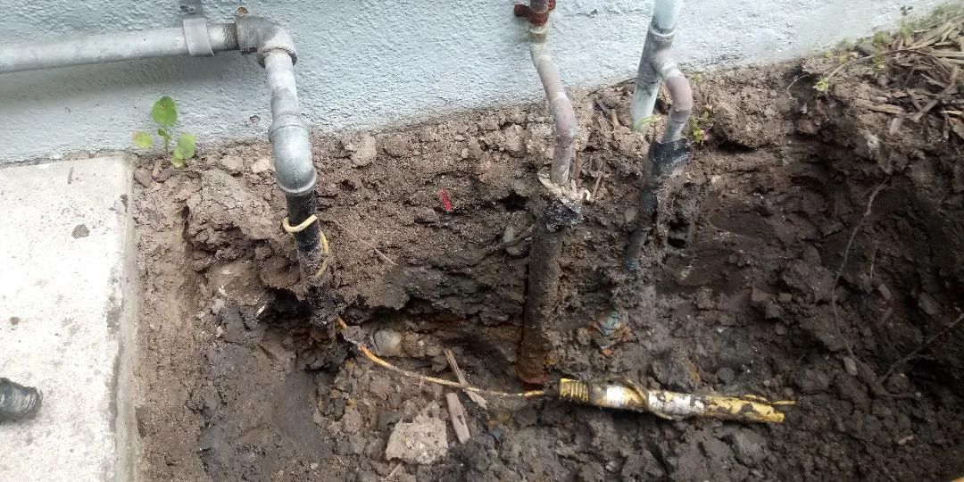 A hole in the ground with pipes coming out of it.