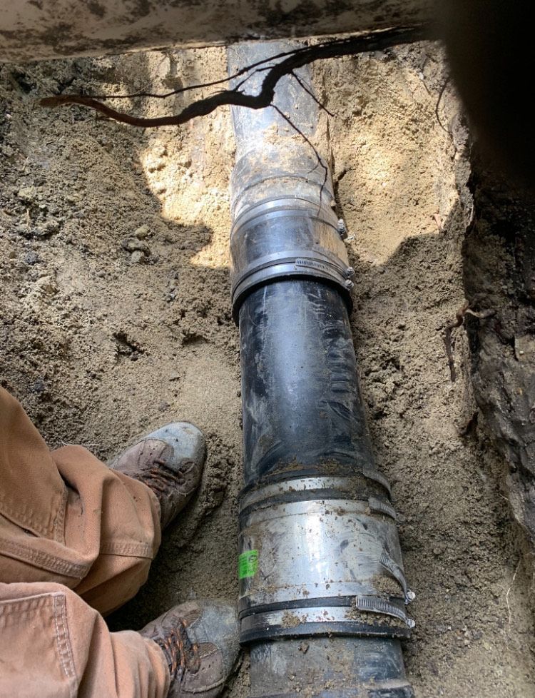 A person is standing next to a pipe in the dirt.