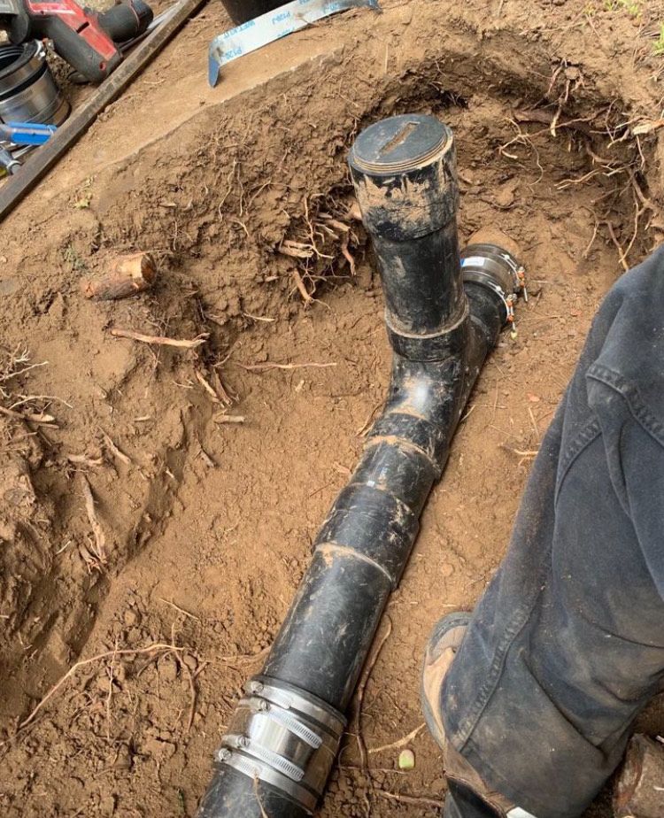 A person is working on a pipe in the dirt.