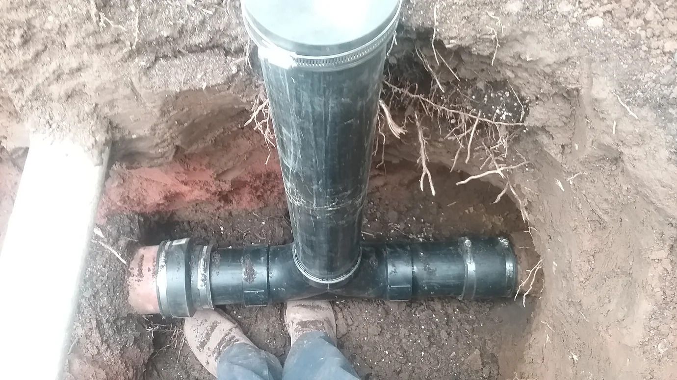 A person is standing next to a pipe in the dirt.