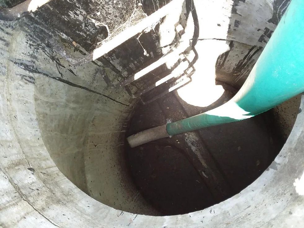 A green pipe is being poured into a hole in the ground